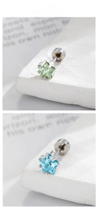 Macro detail of star-shaped gemstone stud earrings in mint green and sky blue