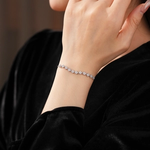 Detailed view of silver clover bracelet with sparkling zircons worn on female wrist