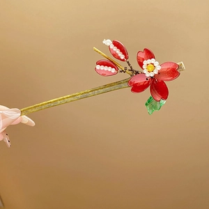 Close-up of red enamel flower hair pin with pearls and tassels in traditional style
