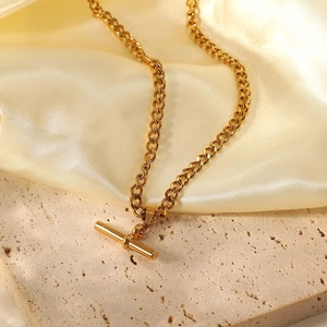 Close-up of golden stainless steel Cuban chain necklace with T-bar toggle clasp on silk