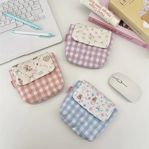 Set of three colorful quilted plaid organizer bags for cosmetics on a modern white desk