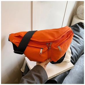 Detailed view of orange crossbody bag featuring multiple zipper pockets and wide black strap