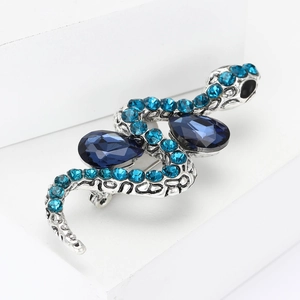 Detailed macro view of silver snake brooch featuring blue rhinestones and teardrop crystals