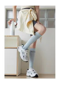 Close-up of light blue slouch socks with letter print paired with white sneakers
