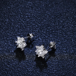 Macro shot of silver moissanite star earrings with six-prong setting on blue leather