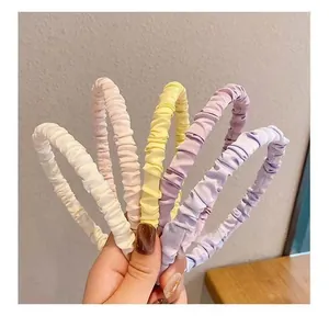 Close-up of five pleated satin scrunchie headbands in pastel macaron colors