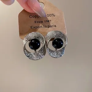 Minimalistische silberne gedrehte Ohrringe mit schwarzer Perle auf Kraftkarton