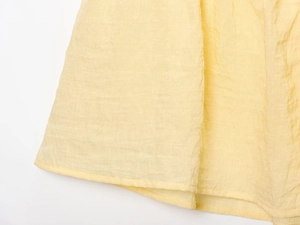 Detail of light yellow pleated fabric showing fine lace trim and neat stitching crafts