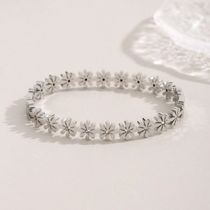 Elegant stainless steel daisy bracelet with sparkling crystal centers on beige background