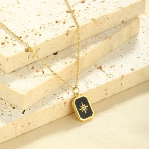 Detail view of gold stainless steel necklace with black zircon star pendant on stone