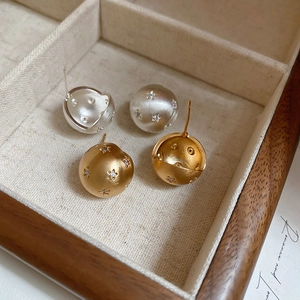 Detailed macro view of brushed gold and silver spherical earrings with zircon stars