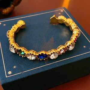 Detail of vintage gold-tone oval open bangle set with colorful multifaceted crystals