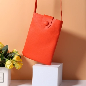 Detail of orange lychee texture phone bag with decorative button and floral accent