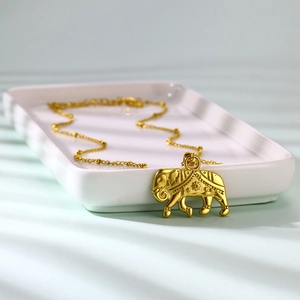 Detail shot of golden elephant pendant necklace on a white tray with ornate carvings