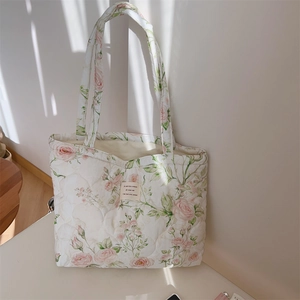 Detail of pink floral quilted cotton tote bag with vintage label and soft shadows