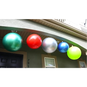 Large outdoor inflatable Christmas balls in multiple vibrant colors hanging on a porch