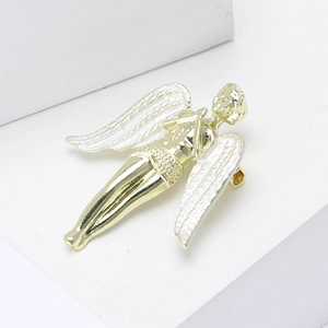 Minimalist golden angel brooch with white enamel wings on a modern geometric display