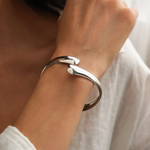 Close-up of polished silver geometric open cuff bracelet on a female wrist