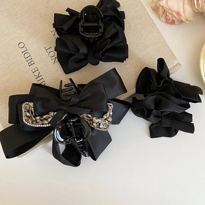 Detailed view of three black satin bow hair claws including a sparkling rhinestone chain detail