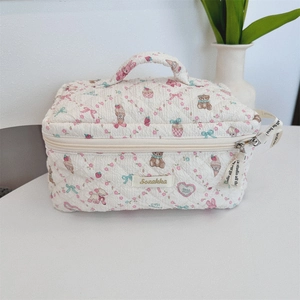 Detail of quilted makeup bag featuring cute bear patterns and top carry handle