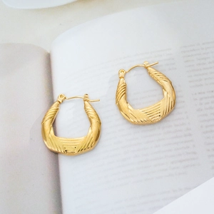 Macro detail of 18K gold plated geometric earrings with twisted spiral texture