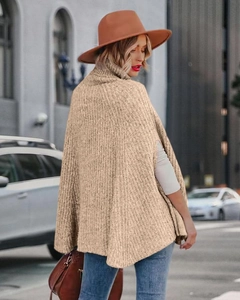 Vista posteriore all'aperto di un poncho kaki a collo alto in maglia a trecce