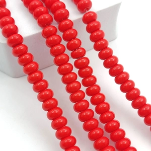 Macro detail of red abacus glass beads arranged on a white display for DIY jewelry