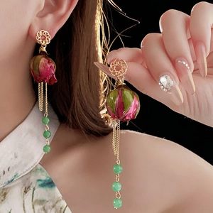 Detail von langen Perlenohrringen mit konservierter Rose und Goldquaste am Modell