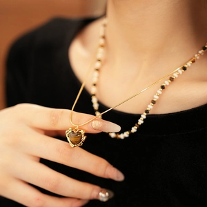 Close-up of a gold-plated heart pendant with tiger eye stone on a sleek snake chain