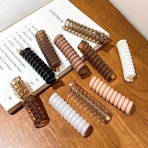 Gros plan de pinces à cheveux spirales colorées sur une table en bois et un livre