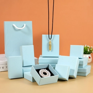 Pale blue jewelry gift box collection with matching paper bags and black velvet padding