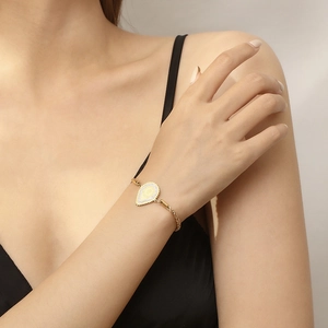 Detail of 18K gold plated teardrop pendant with twisted chain on a model's wrist