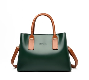 Detail view of leather handbag with deep green body and brown handles with gold hardware
