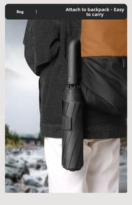 Close-up of black automatic umbrella with U-shaped hook handle hanging on a backpack