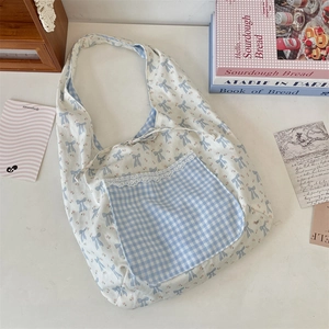 Détail du sac cabas en toile avec motifs de nœuds bleus et bordure en dentelle