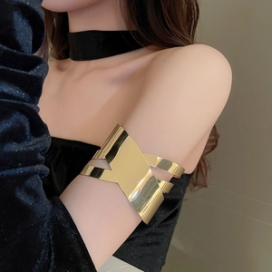 Dettaglio di un ampio bracciale da braccio geometrico dorato lucido su un braccio superiore
