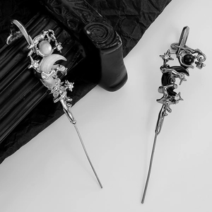 Macro shot of gothic star and moon hair pins with rhinestones on black background