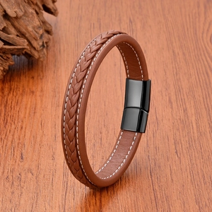 Close-up of men's brown braided leather bracelet with white stitching and magnetic clasp