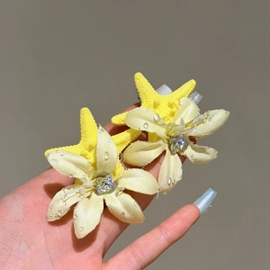 Nahaufnahme von eleganten gelben Stoffblumen-Haarspangen mit Seestern-Akzenten und Perlen