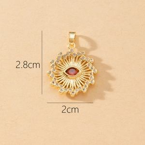 Detail of a 2.8x2cm sunburst evil eye pendant with red gem and clear crystals