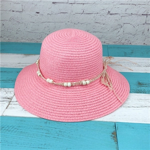 Close-up of pink woven sun hat with cream beaded rope strap and decorative bow detail