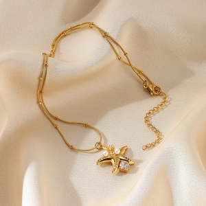 Detailed macro view of gold starfish pendant with pearls and zircon on silk background