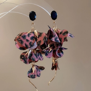 Macro shot of bohemian pink leopard print fabric flower earrings with gold leaf charms
