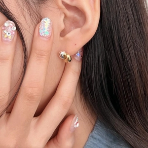 Close-up of two-tone knot earrings with gold and silver intertwining rings on model