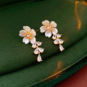 Detail of flower earrings with mother of pearl and zircon droplets on green velvet