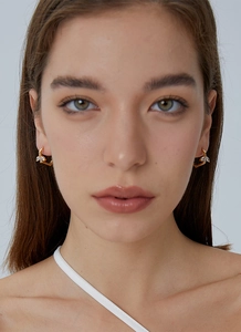 Detail of elegant gold earrings with leaf-shaped zircon stones worn by a model