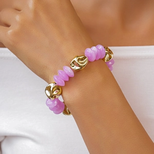 Detailed shot of retro acrylic purple beads and irregular gold charms on a chunky bracelet