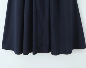 Dettaglio dell'orlo dell'abito blu navy che mostra il drappeggio del tessuto di qualità