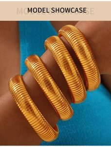 Close-up of four stacked gold-plated titanium steel bangles with textured ridges on wrist