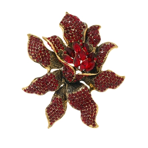 Vintage floral brooch with red rhinestones set in gold metal on a white background